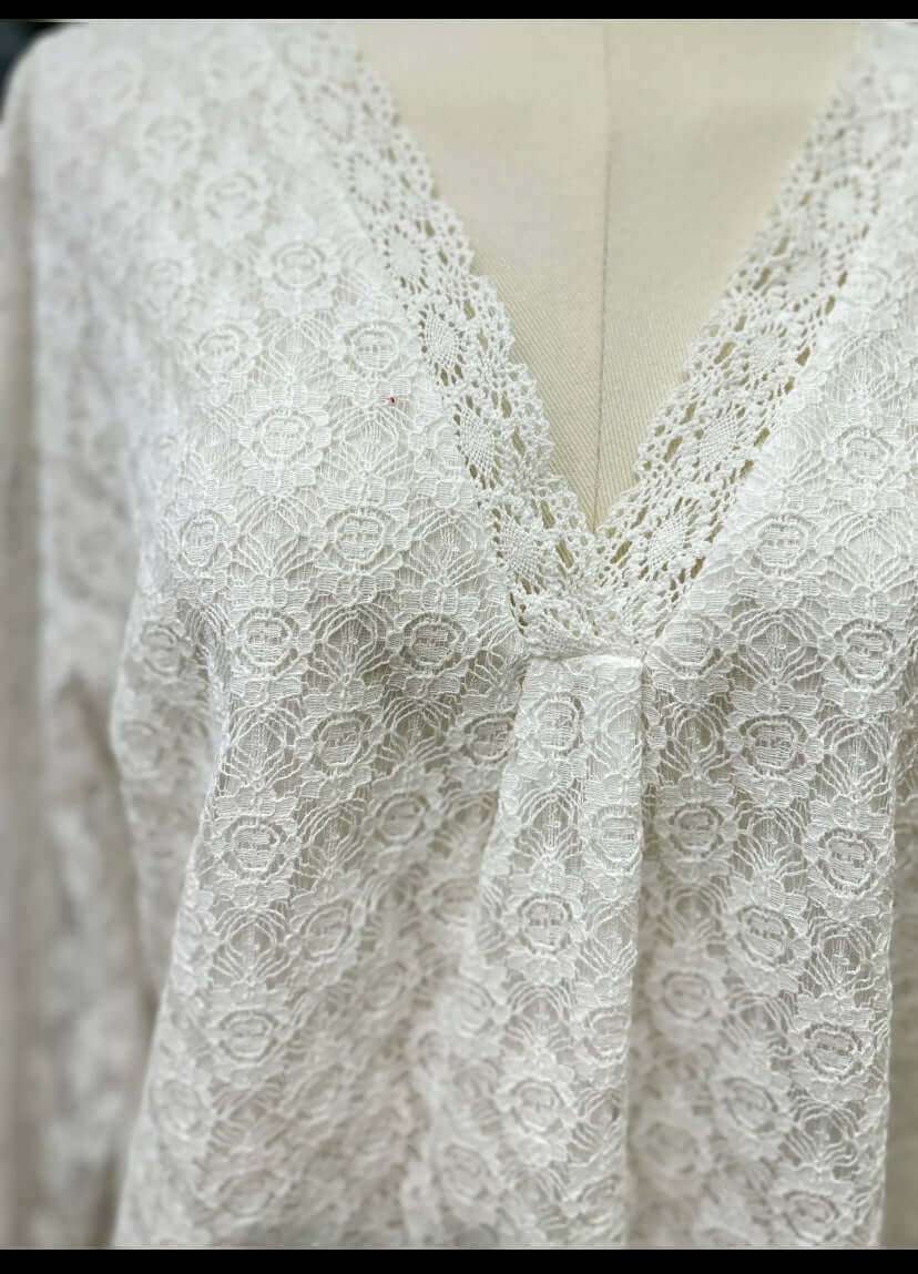 Zoom sur le tissu du haut en dentelle blanche Luna Chic – détails floraux délicats et col V festonné élégant