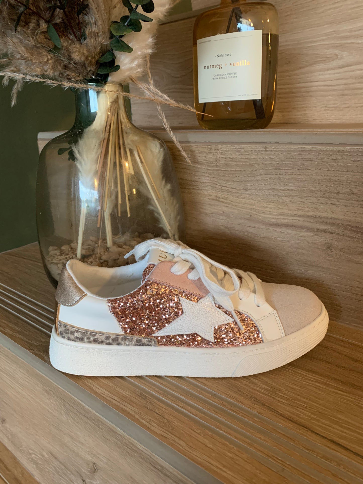 Basket blanche à paillettes rose gold Luna Chic posée sur une marche en bois, étoile blanche sur le côté