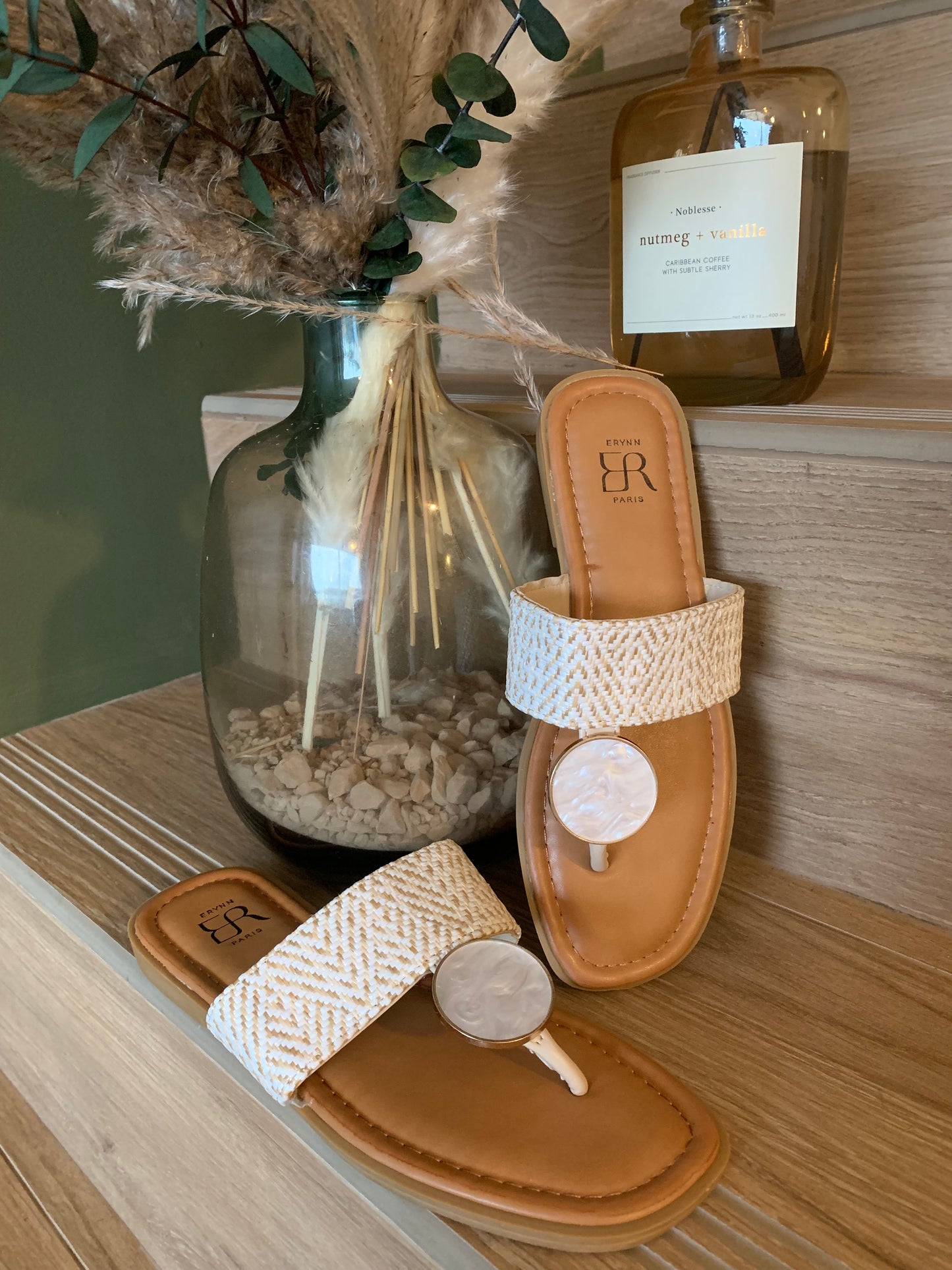 Sandales plates Luna Chic avec anneau nacré et bande tissée beige posées en décor sur fond bois, ambiance naturelle chic