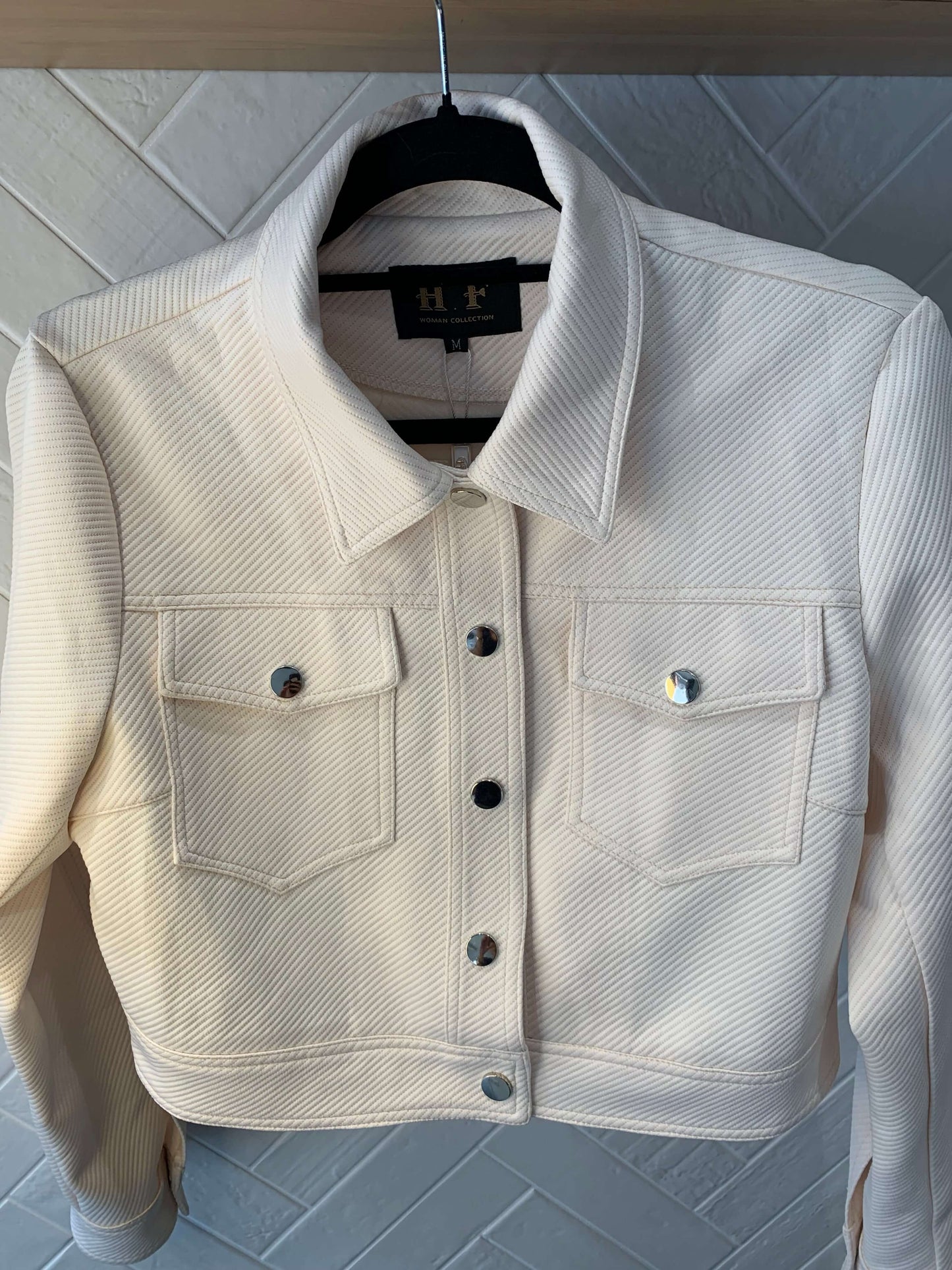 Veste courte texturée Luna Chic beige – vue à plat sur cintre, boutons métal argenté, lumière naturelle