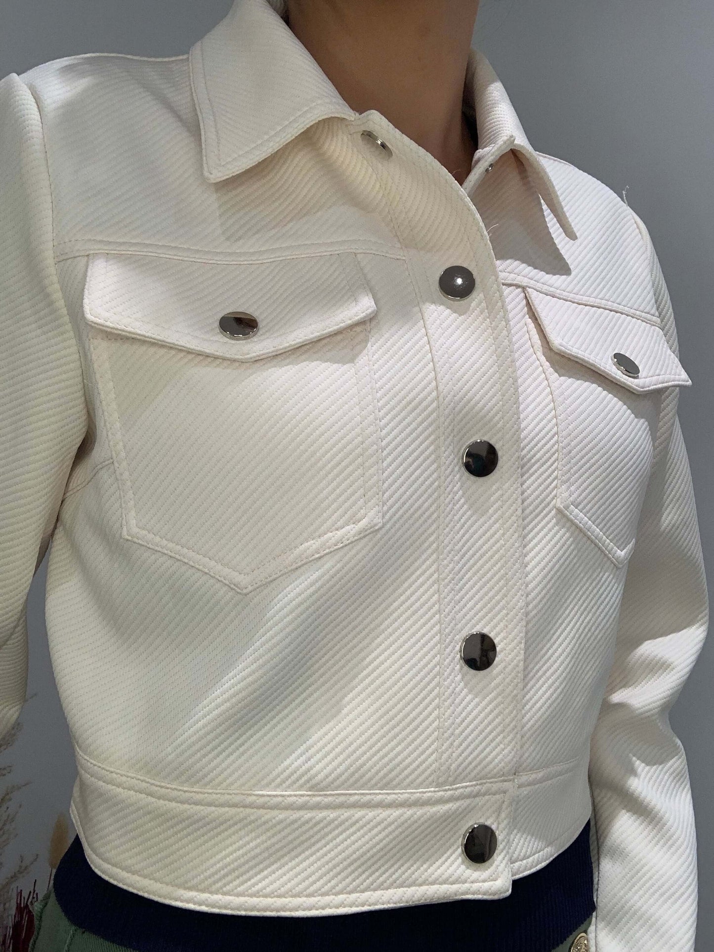 Veste courte Luna Chic crème – vue portée légère en biais, tissu texturé et boutons métal
