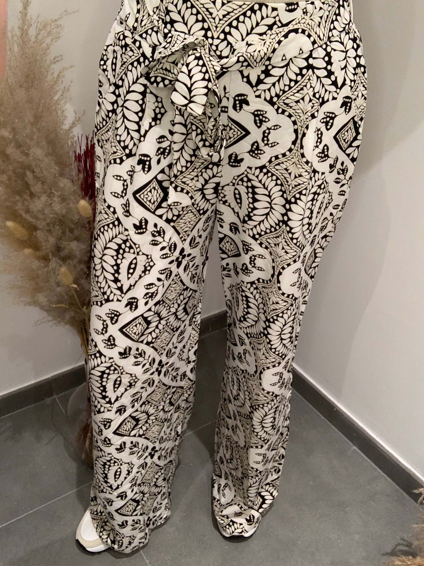 Pantalon fluide Luna Chic porté de face avec imprimé noir et blanc et ceinture nouée