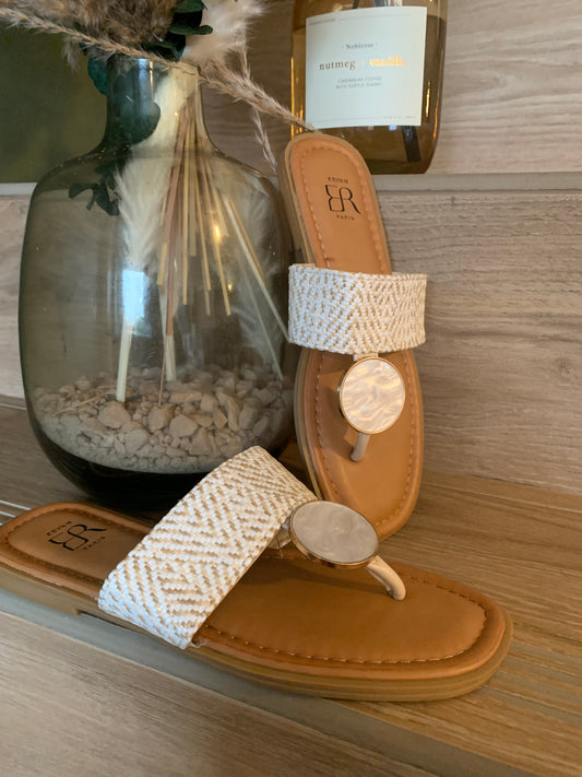 Sandales plates Luna Chic avec anneau nacré et bande tissée beige, exposées sur fond bois naturel avec vase déco