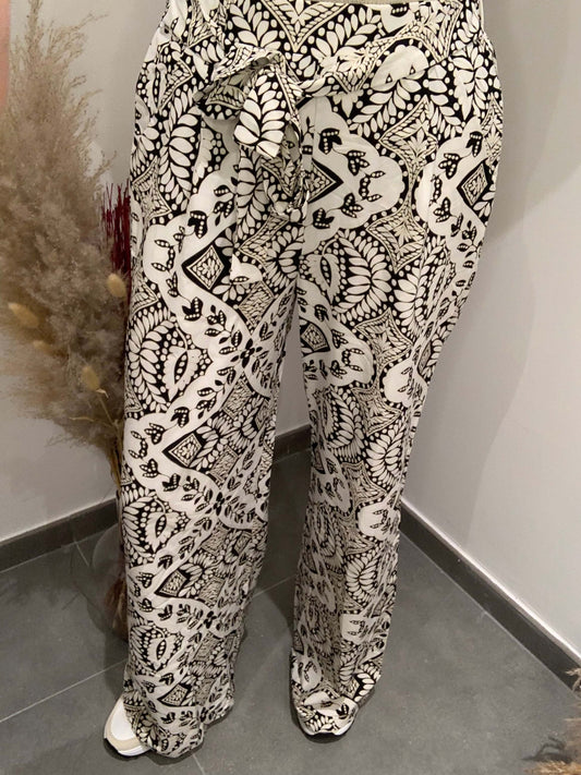 Pantalon fluide Luna Chic porté de face avec imprimé noir et blanc et ceinture nouée